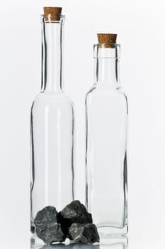 Empty glass bottles with corks and stones on white background