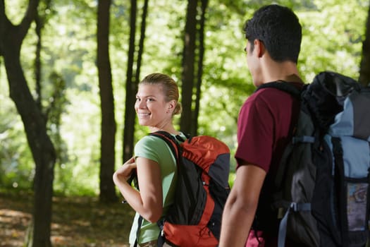 young man and woman during hiking excursion, with woman looking over shoulders. Horizontal shape, rear view, waist up
