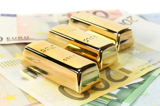 Gold bars and euro notes against light background
