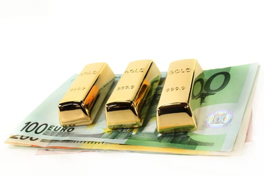 Gold bars and euro notes against light background