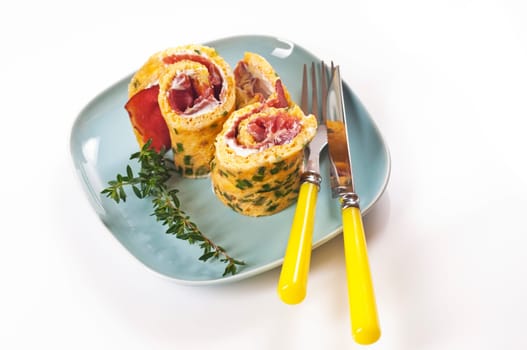 Omelette roll with ham and cream cheese on blue plate