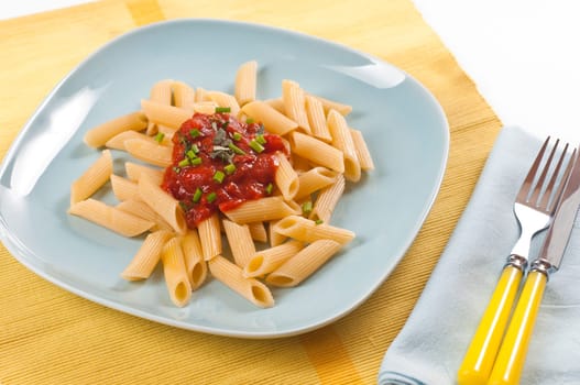 Pasta with tomato sauce and fresh chives on blue dishes