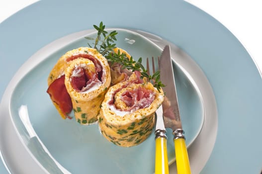 Omelette roll with ham and cream cheese on blue plate