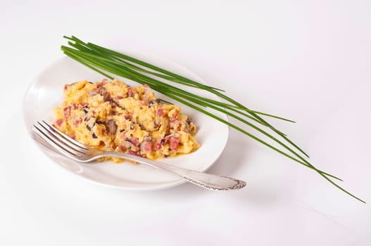 Scrambled eggs with bacon and onions on white plate