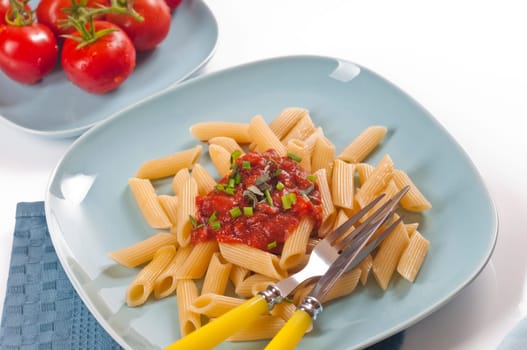 Pasta with tomato sauce and fresh chives on blue dishes