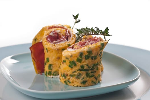 Omelette roll with ham and cream cheese on blue plate