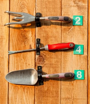 A set of garden tools on display fastened to a wooden board