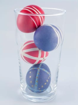 four Easter Eggs in a glass isolated on white background