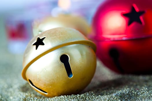 Close-up of golden and red jingle bell Christmas baubles with candles