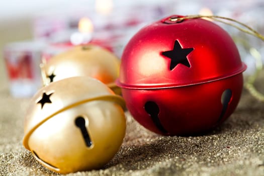 Close-up of golden and red jingle bell Christmas baubles with candles