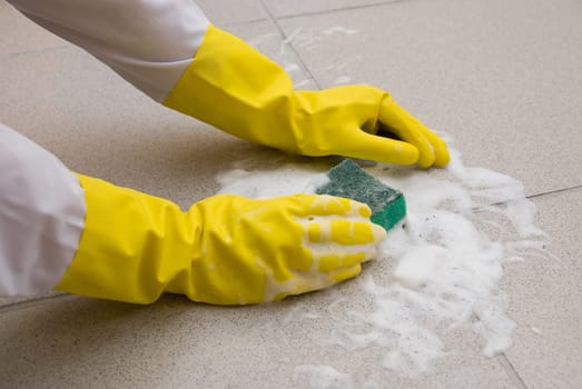 Hands in yellow gloves with sponge, washing floor