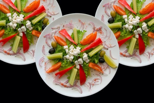 Group of plates with salad on black background.
