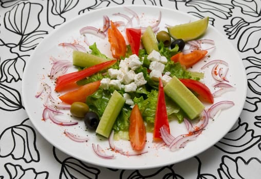 Appetizing salad in a plate on stylish black and white tablecloth