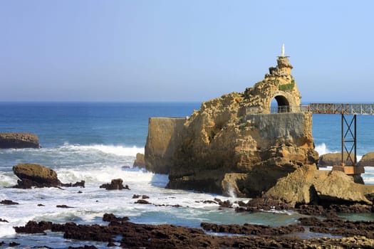 panoramic views of the ocean with its rocks and waves over a blue sky
