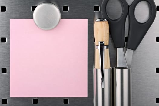 Notepads,scissors and pens with magnet on pin board.