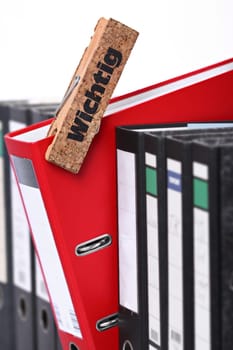 A row of black file folders with an important red one.