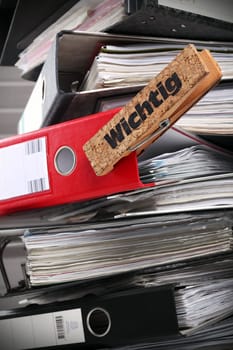 A stack of black files with an important red one.