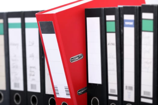 A row of black file folders with an important red one.