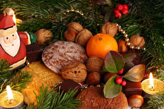 Sweets by candlelight with fir branches and decoration.