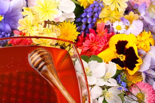 Glass bowl with honey and measuring spoon in flowers