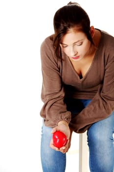 Pretty woman sitting on a chair a holding heart in her hand.