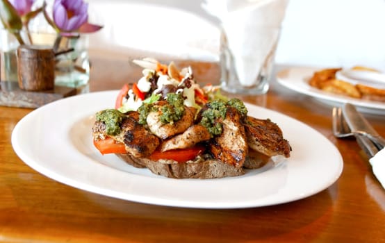 horizontal landscape of plated main course of pepper grilled chicken tomato salad mayo on bed of tofu table accessories mustard pot white plate cutlery home fries water glass crop space copy area