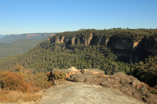 A view of a cliff line with smooth rocks in the foreground