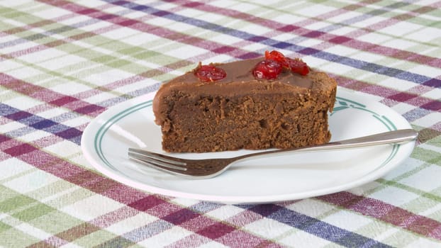 A chocolate cherry cake on a stripped table cloth