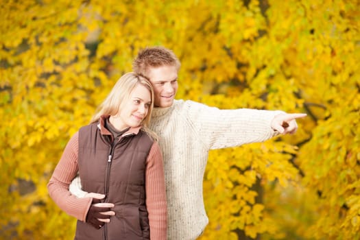 Autumn romantic couple happy together hugging in park pointing