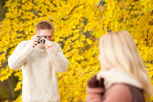 Young man make photo of posing woman profile in autumn park
