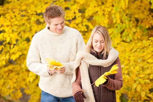 Young couple picking leaves in autumn park outfit