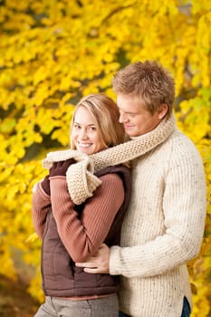 Smiling young couple in love hugging in autumn park together