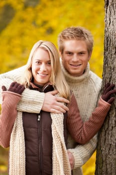 Smiling young couple in love hugging in autumn park together