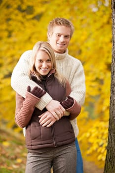 Smiling young couple in love hugging in autumn park together