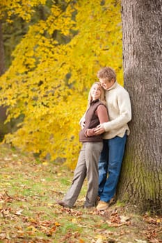 Smiling young couple in love hugging in autumn park together