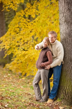 Autumn romantic couple happy together hugging in park pointing