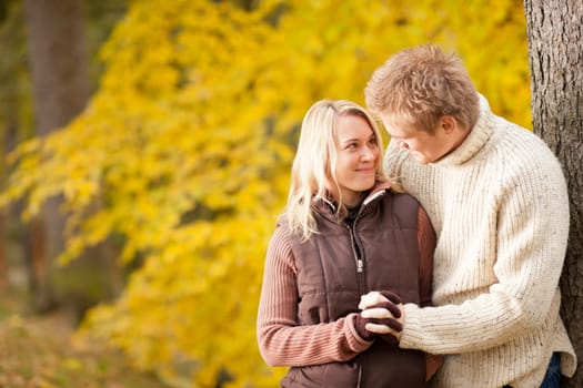 Smiling young couple in love hugging in autumn park together