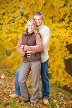 Smiling young couple in love hugging in autumn park together