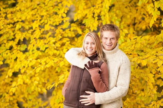 Autumn smiling young couple in love hugging in park together