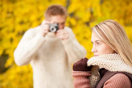 Young man make photo of posing woman profile in autumn park