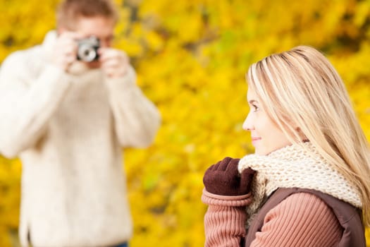 Young man make photo of posing woman profile in autumn park