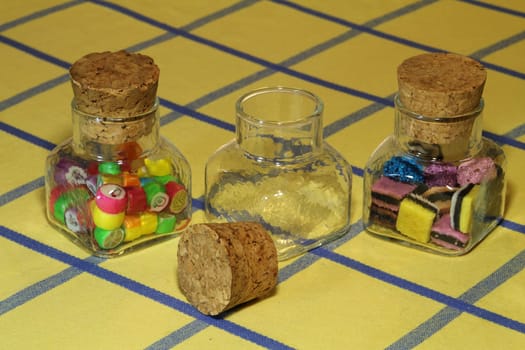 Three small lolly jars on a table with the centre lolly jar empty