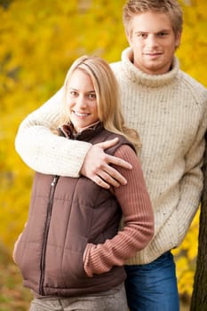 Smiling young couple in love hugging in autumn park together
