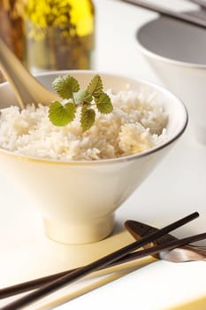 Rice an a bowl with chopsticks and oil in the background