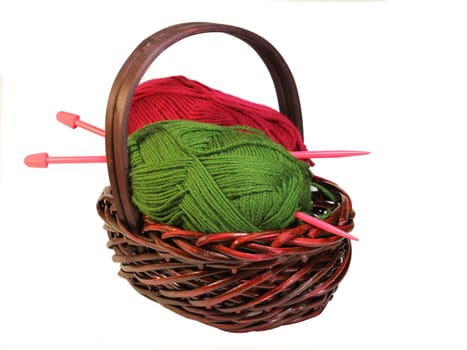 A basket with green and red balls of wool