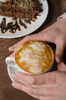 Closeup of female hands holding cup of Cappuccino