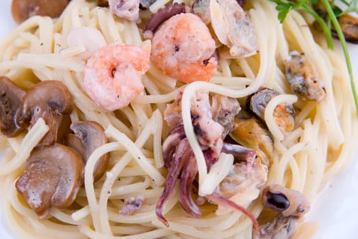spaghetti with seafood and mushrooms on white plate