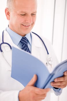 Professional senior doctor male with stethoscope look down document folders