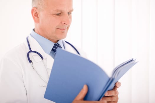 Professional senior doctor male with stethoscope look down document folders
