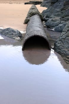 a rusty overflow pipe coming from the land to the sea